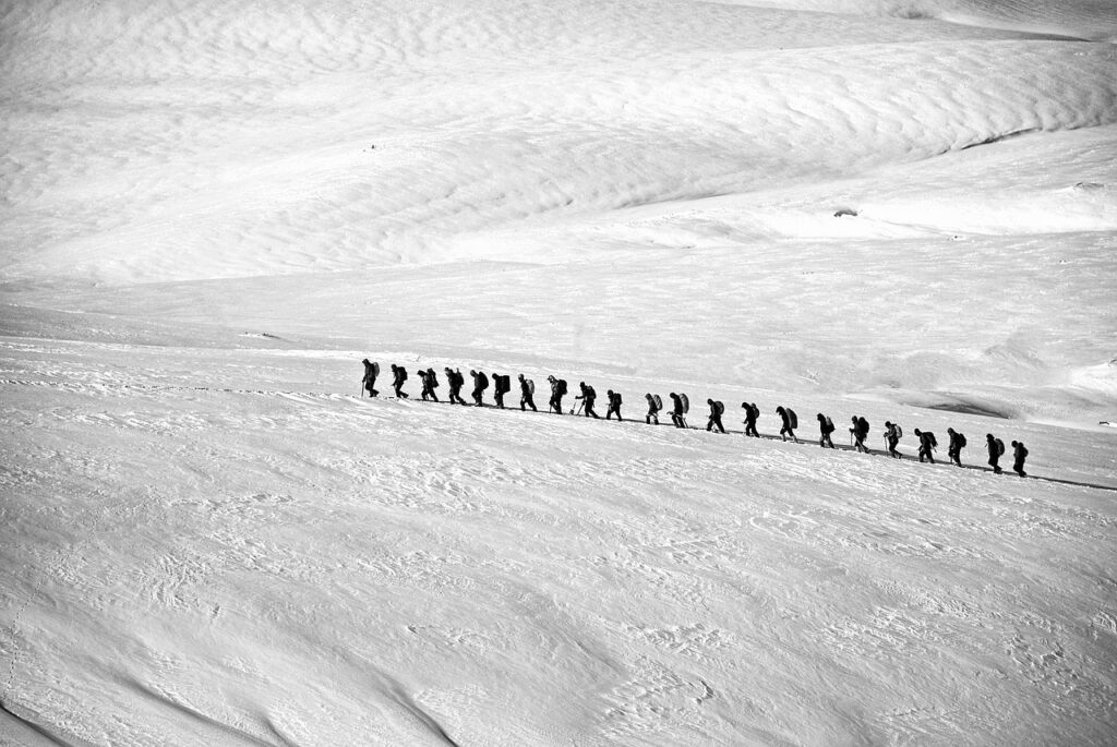Photo of a line of people hiking through the snow.