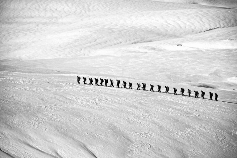 Photo of a line of people hiking through the snow.