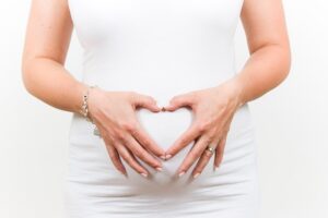 Pregnant woman making heart shape with hands over stomach
